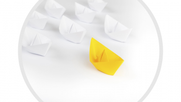 Image of a yellow paper boat with white paper boats behind it